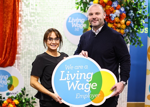Two people standing in front of a sign that reads "We are a Living Wage Employer".