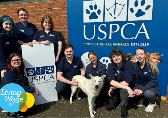 Eight people and a dog standing in front of the USPCA banner.