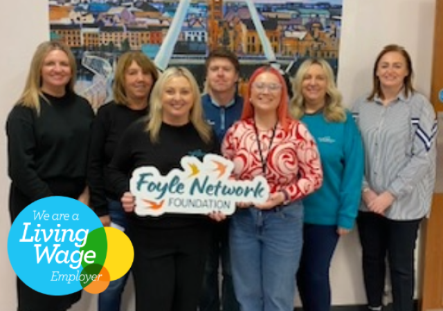 Seven people standing with one person holding the Foyle Network Foundation logo.