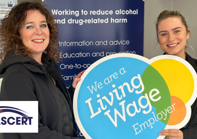 Two people standing beside a prop that says "We are a Living Wage Employer".